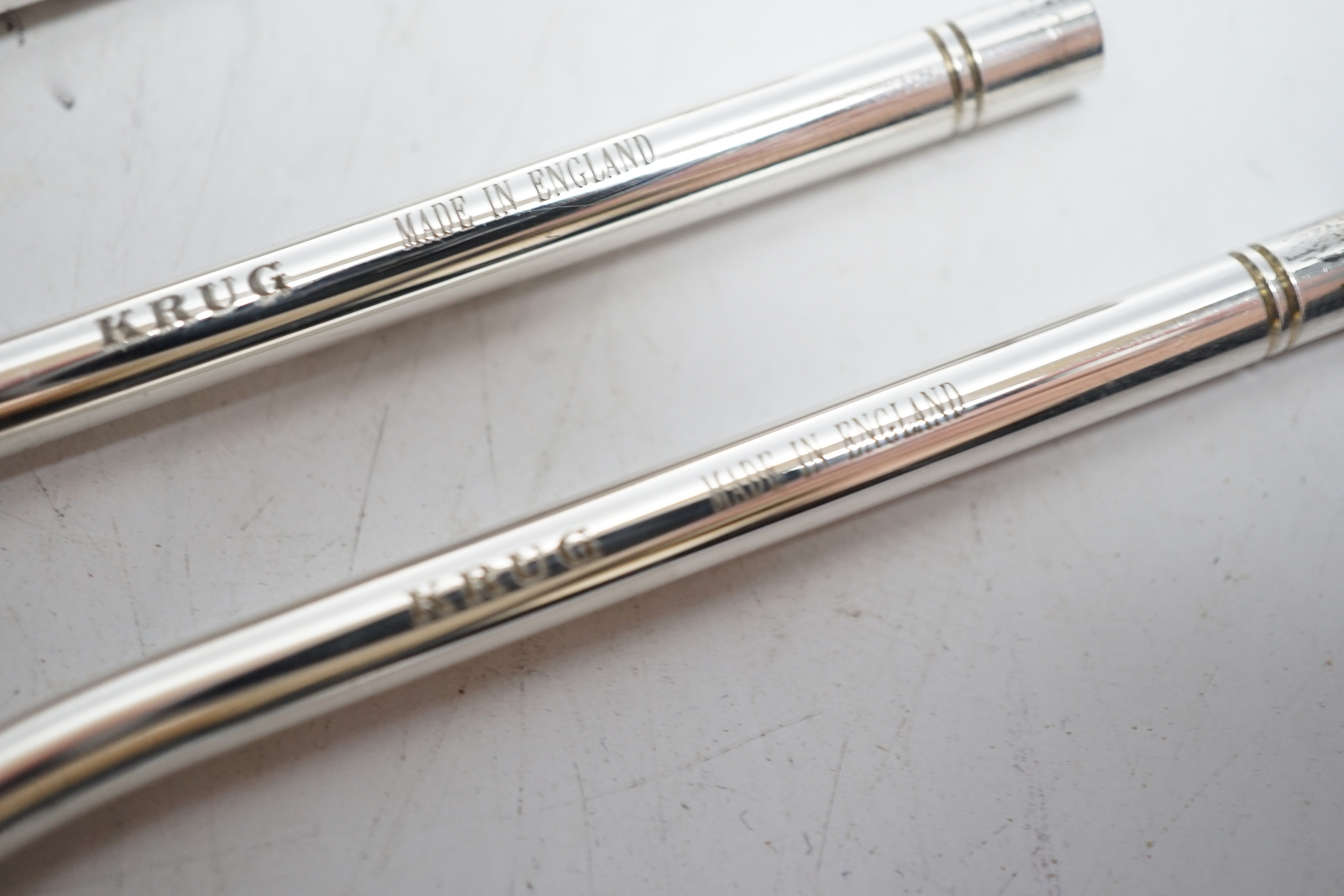 Four modern silver Krug Champagne straws, with original covers, 26.5cm.